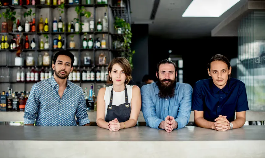 Diverse Bar Staff Team Behind Counter Four diverse bar professionals standing behind counter in a bar setting in business directory